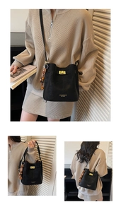 Détail du sac seau en cuir noir avec fermoir doré et pendentif décoratif en perles