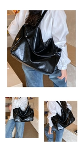 Close-up of a large black glossy leather tote bag with a minimalist design for women