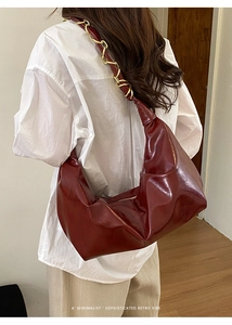 Deep red retro dumpling bag with gold chain strap shown on model for size and drape