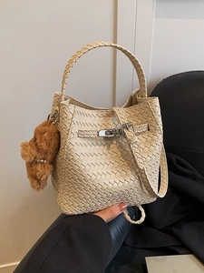 Cream woven bucket bag with silver metal buckle and brown plush bear charm on strap