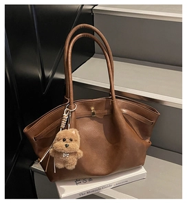 Detail of a brown vintage tote bag with pleated side design and a plush puppy charm
