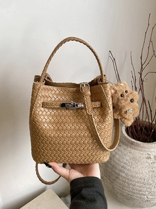 Fashionable tan woven bucket bag with silver twist lock and cute plush dog charm