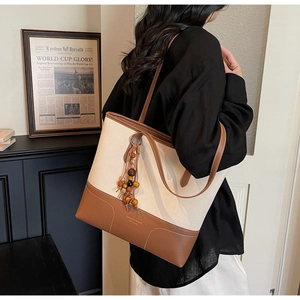 Detail of canvas tote bag with leather trim and colorful bohemian beaded tassel charm