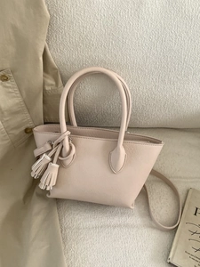 Cream lychee leather bucket handbag with twin tassels for women in fashion setup