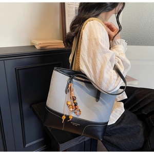 Detail of grey canvas tote bag with leather base and wooden bead tassel ornament