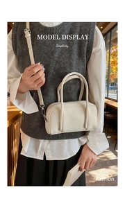 Chic cream leather Boston bag styled with casual outfit in a cozy cafe setting