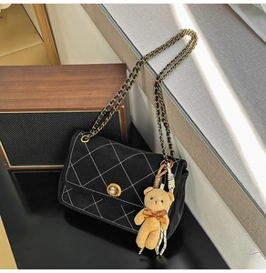 Detail of black quilted crossbody bag with gold twist lock and cute plush bear charm