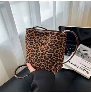 Détail du sac seau léopard en velours avec fine bandoulière marron sur un bureau