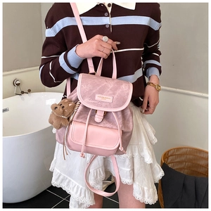 Detailed close-up of pink frosted leather backpack with cute bear pendant and metal logo