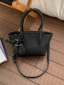 Classic black matte tote bag with dual tassels and adjustable strap shown from a top view