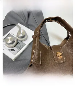 Close-up of deep brown lychee texture leather bucket bag with golden twist lock