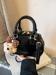 Glossy black Boston crossbody bag with a plush bear charm and golden buckle details