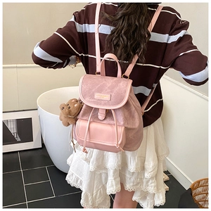Pink matte backpack detail with a cute brown plush bear pendant and fashion logo