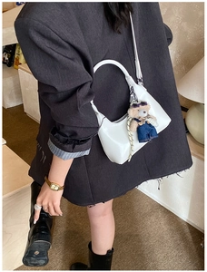 Detailed view of white moon bag with leather texture and cute denim bear pendant charm