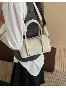 Detailed side view of a minimalist cream Boston bag with silver hardware and shoulder strap
