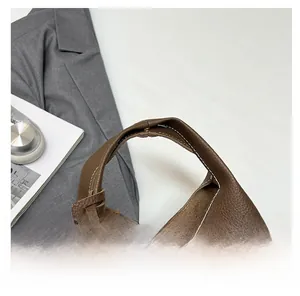 Detail of dark brown lychee leather handbag with white contrast stitching and gold lock