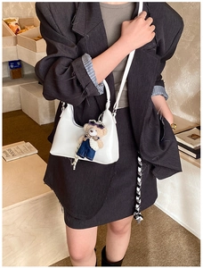 Chic white retro shoulder bag styled with a cute bear charm pendant in a cafe setting