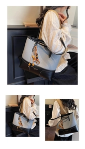 Close-up of grey patchwork tote bag with black leather straps and wooden bead tassel