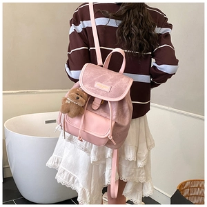 Detailed back view of pink matte leather backpack with a cute plush bear charm on model