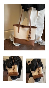 Detailed view of canvas tote bag with leather trim and colorful wooden bead tassel