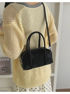 Close-up of black textured Boston bag with silver hardware held by a model in yellow