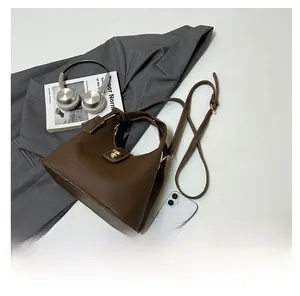 Detail of a dark brown lychee pattern leather handbag with metal turn-lock and accessories