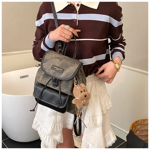 Detail view of retro grey-black patchwork backpack with soft texture and plush dog charm