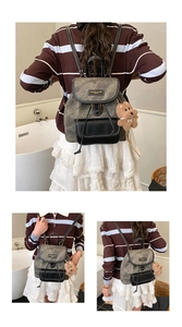 Detail of gray washed fabric backpack with black faux leather trim and plush bear charm