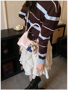 Pink patent leather hobo bag with a cute bear charm accessory on a model