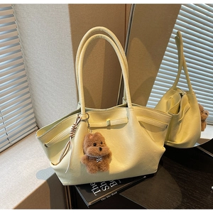 Detail shot of cream tote bag with cute bear charm and tassel on a book