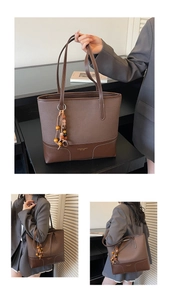 Detail of dark brown leather tote bag with ethnic beaded charm and brand logo print