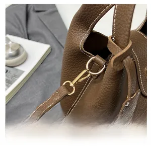 Detailed macro of golden metal hook and contrast stitching on brown leather bucket bag