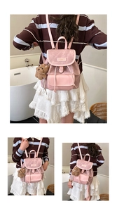 Detailed view of pink faux leather backpack with drawstring closure and plush bear charm