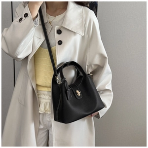 Detail of black pebbled leather bucket bag with gold twist lock and white stitching
