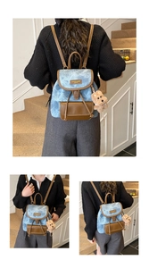 Detail of blue denim backpack with brown leather flap and cute teddy bear charm