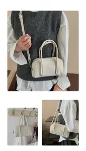 Detail of a minimalist cream Boston handbag with adjustable straps and textured finish