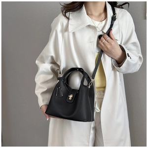 Detail of black lychee grain leather handbag with gold twist lock and dual handles