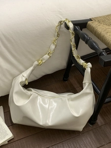 Creamy white glossy hobo bag with pleated leather and gold chain strap in room setting