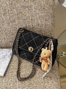 Quilted black suede crossbody bag with gold hardware and plush bear charm