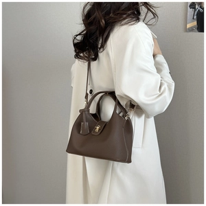 Detail of dark brown lychee leather handbag with gold twist lock and fine stitching
