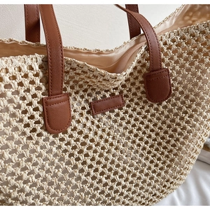 Detail of woven straw tote bag with brown leather straps and smooth beige lining