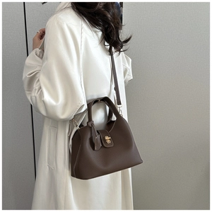 Detail view of dark coffee leather handbag with side fold and gold turn-lock