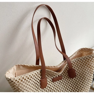 Close-up of woven straw tote bag featuring interior fabric lining and brown faux leather straps