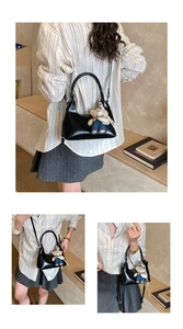 Detail showing glossy black underarm bag with cute teddy bear charm on adjustable strap