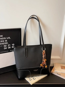 Retro black leather tote bag with white contrast stitching and a beaded tassel charm