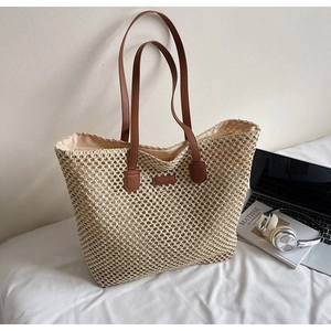 Detailed macro of the woven straw tote bag mesh texture with brown leather handles