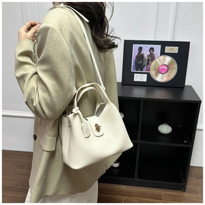 Detail view of cream leather handbag with gold twist lock and fine lychee grain texture
