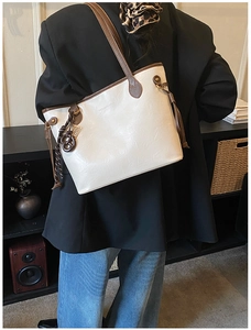 Detail of vintage beige tote bag with brown handles and elegant side drawstring accents