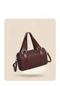 Detail of lightweight reddish-brown woven cylindrical handbag with silver metal rings