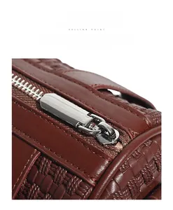 Detail of smooth metal zipper and brown woven leather texture on a shoulder bag